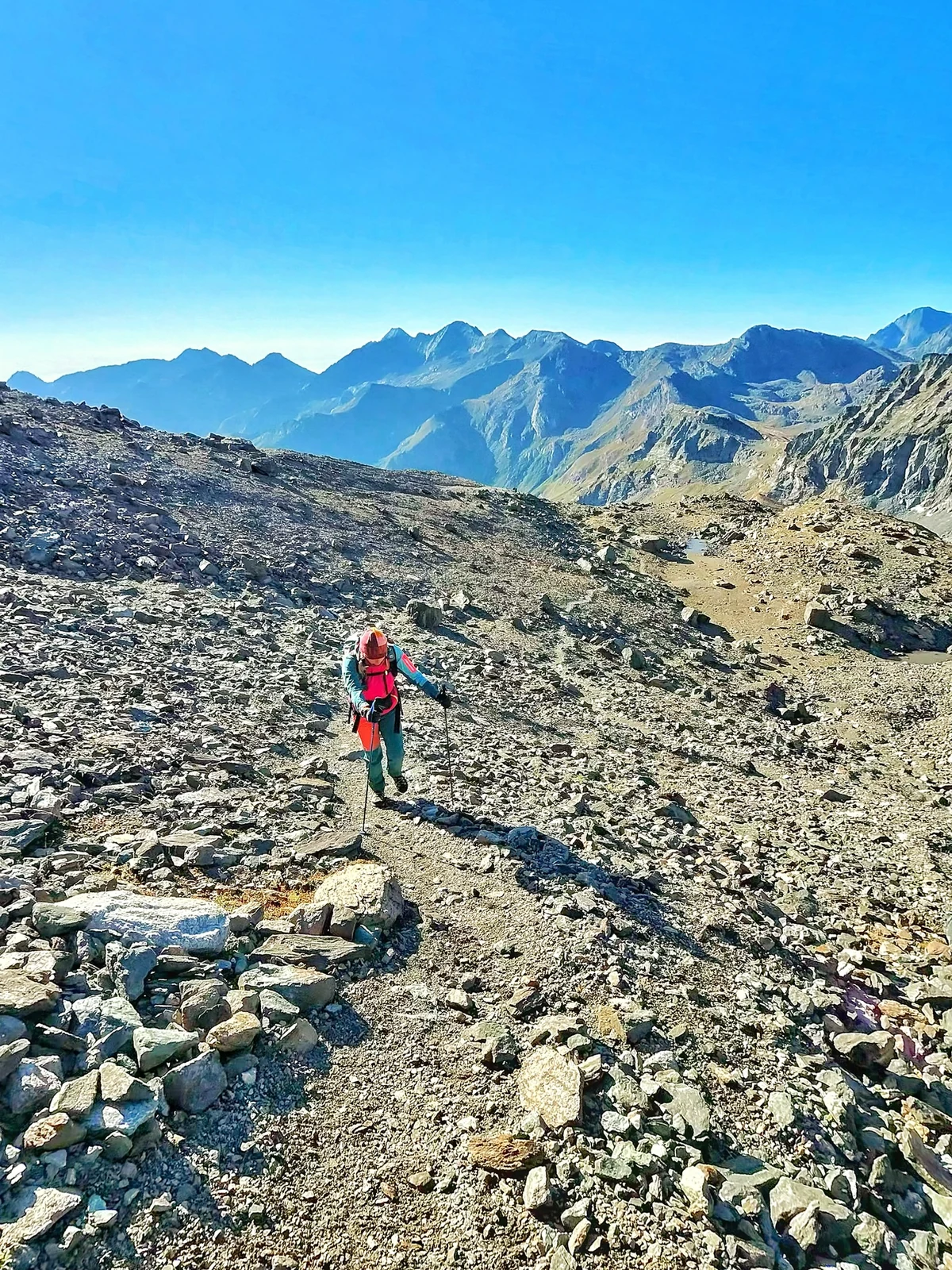 Una figura in salita sulla pietraia con le Alpi sullo sfondo